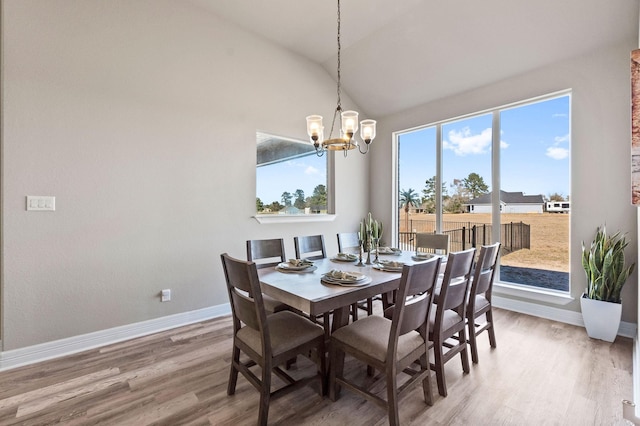 dining room with hardwood / wood-style floors, an inviting chandelier, and lofted ceiling