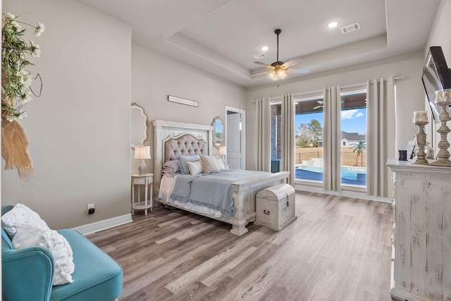 bedroom featuring ceiling fan, wood-type flooring, and a tray ceiling