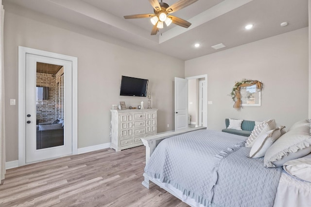 bedroom with light wood-type flooring, ceiling fan, and a raised ceiling