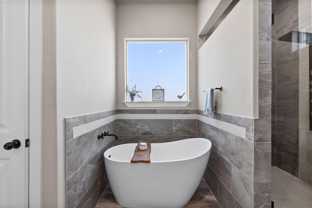 bathroom with tile walls and separate shower and tub