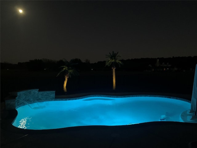 pool at twilight featuring pool water feature