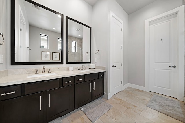 full bath with double vanity, baseboards, a tile shower, and a sink