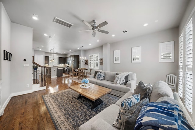 living room with ceiling fan with notable chandelier and dark hardwood / wood-style floors