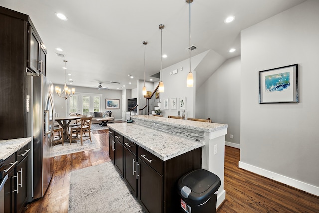 kitchen with a center island, stainless steel refrigerator with ice dispenser, hanging light fixtures, open floor plan, and dark brown cabinets