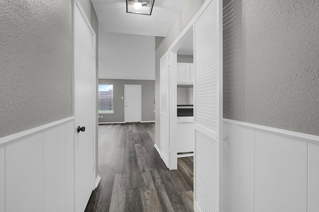 corridor with dark hardwood / wood-style floors and a textured ceiling