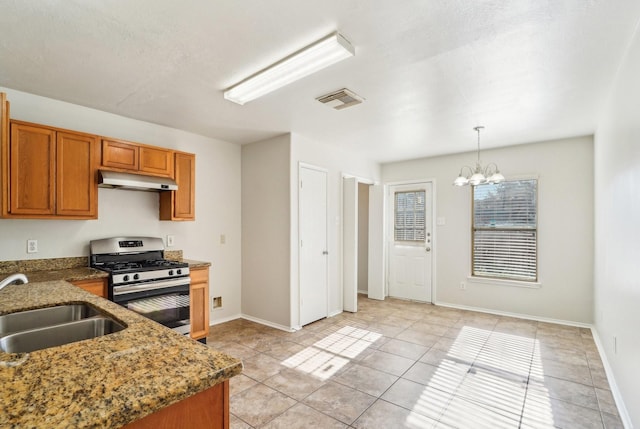 kitchen with stainless steel gas stove, hanging light fixtures, sink, light tile patterned floors, and a notable chandelier