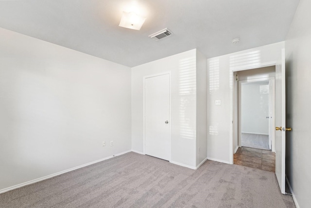 unfurnished bedroom featuring light carpet and a closet