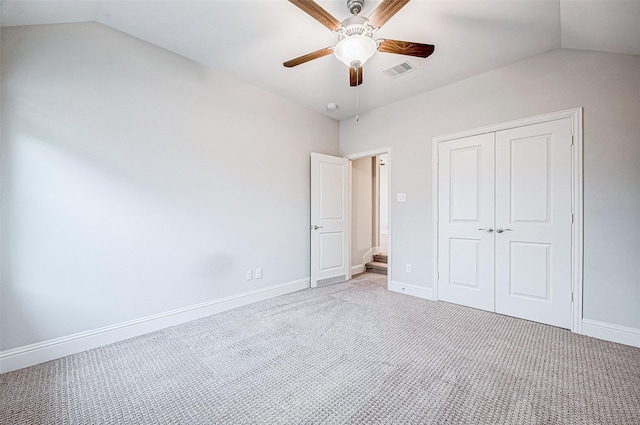 unfurnished bedroom featuring a closet, ceiling fan, light colored carpet, and lofted ceiling