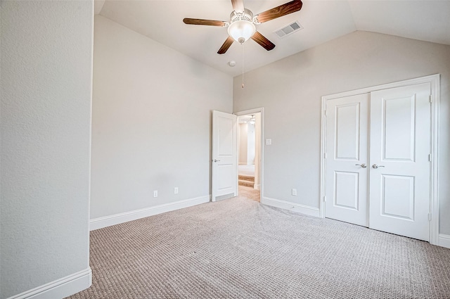 unfurnished bedroom featuring ceiling fan, carpet, a closet, and vaulted ceiling