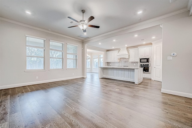 unfurnished living room with crown molding, light wood-type flooring, and ceiling fan