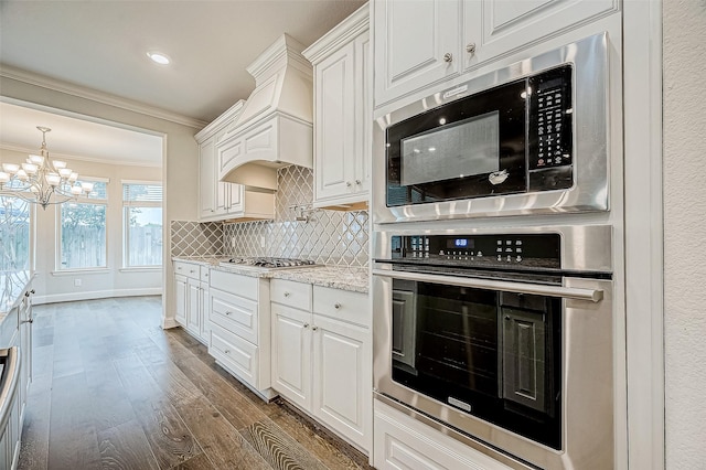 kitchen with white cabinets, appliances with stainless steel finishes, dark wood-type flooring, backsplash, and crown molding