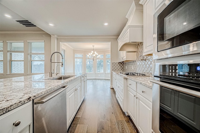 kitchen with pendant lighting, appliances with stainless steel finishes, white cabinets, sink, and backsplash