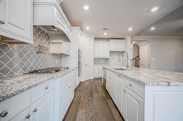 kitchen featuring white cabinets, appliances with stainless steel finishes, dark wood-type flooring, sink, and a center island with sink