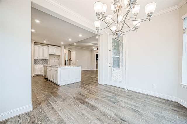 kitchen featuring decorative light fixtures, sink, white cabinets, tasteful backsplash, and a kitchen island with sink