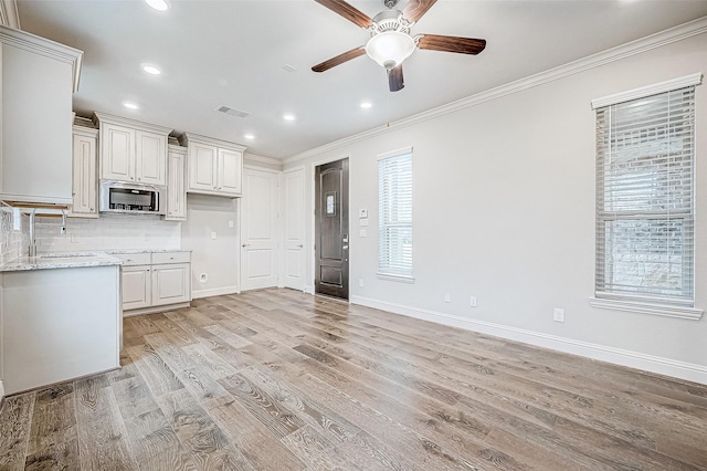 kitchen featuring sink, light wood-type flooring, light stone countertops, and crown molding