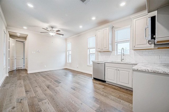 kitchen with appliances with stainless steel finishes, sink, white cabinetry, tasteful backsplash, and light hardwood / wood-style floors