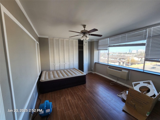 unfurnished bedroom with ceiling fan, dark hardwood / wood-style flooring, a wall unit AC, and ornamental molding