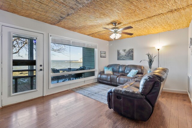 living room with hardwood / wood-style flooring, brick ceiling, a water view, and a wealth of natural light