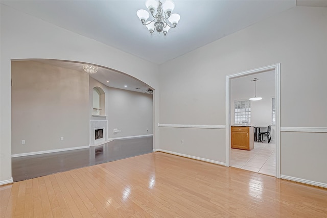 unfurnished living room featuring an inviting chandelier and light wood-type flooring