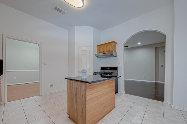 kitchen with a kitchen island, light tile patterned floors, and stove