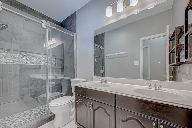 bathroom featuring a shower with shower door, toilet, vanity, and tile patterned flooring