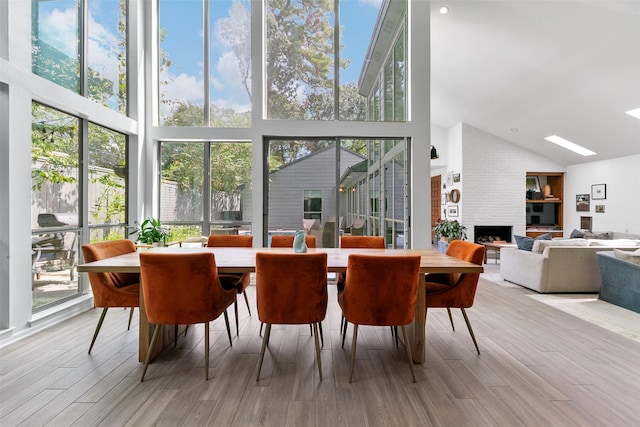 dining area with a fireplace, light hardwood / wood-style flooring, and a towering ceiling