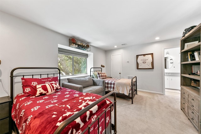 bedroom featuring connected bathroom and light colored carpet