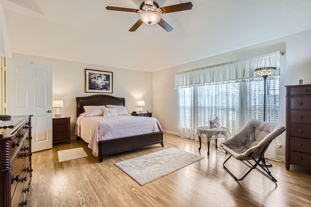 bedroom featuring ceiling fan, a raised ceiling, vaulted ceiling, and light wood-type flooring