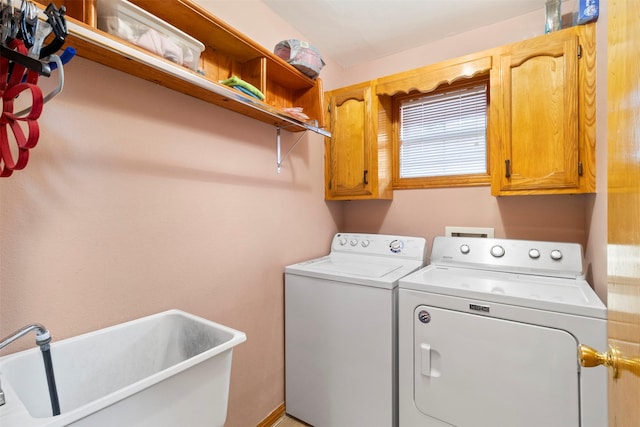 clothes washing area with sink, independent washer and dryer, and cabinets