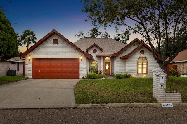 view of front of home featuring a garage, cooling unit, and a lawn