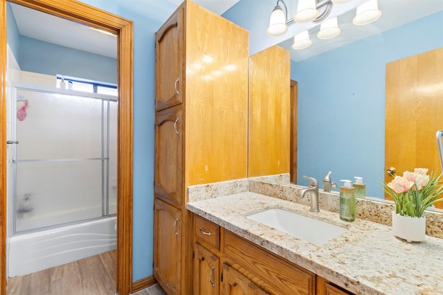 bathroom with hardwood / wood-style floors, combined bath / shower with glass door, and vanity