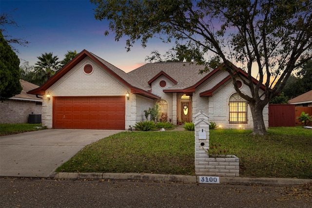 view of front of house featuring a garage, central AC unit, and a lawn