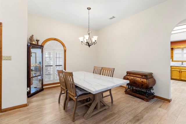 dining room with light hardwood / wood-style flooring and a notable chandelier