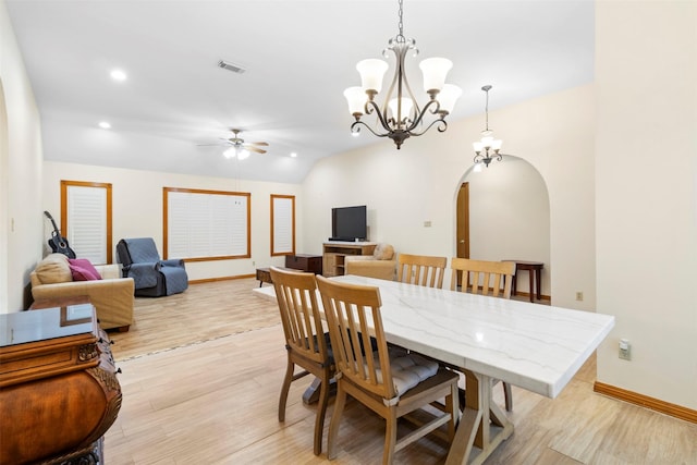 dining area featuring ceiling fan with notable chandelier, vaulted ceiling, and light wood-type flooring