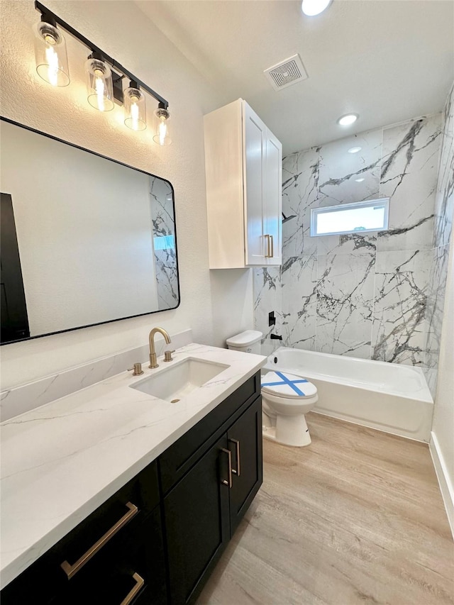 full bathroom with hardwood / wood-style flooring, toilet, vanity, and tiled shower / bath