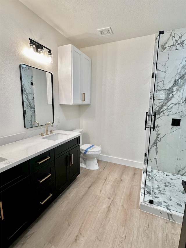 bathroom with a textured ceiling, walk in shower, hardwood / wood-style floors, and vanity