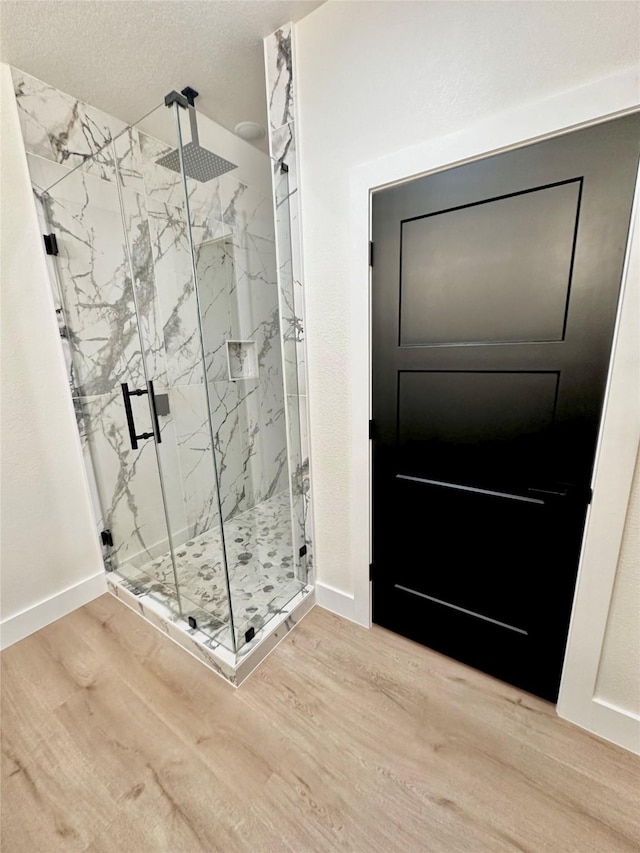 bathroom featuring hardwood / wood-style floors, an enclosed shower, and a textured ceiling