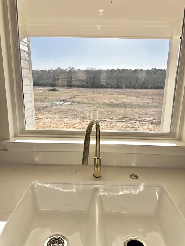 interior details featuring light stone counters, sink, and a rural view