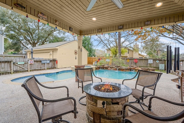 view of pool featuring a patio, ceiling fan, and a fire pit