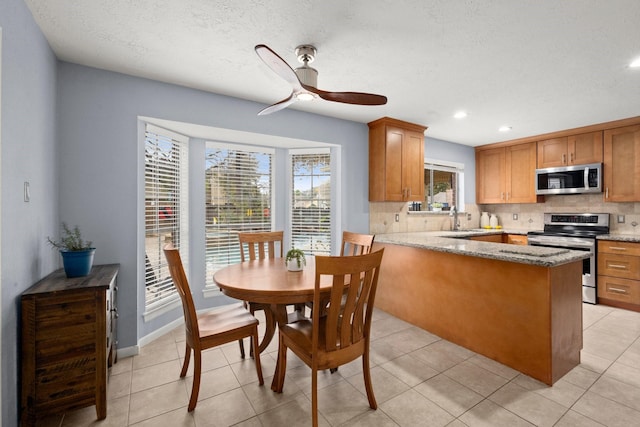 kitchen featuring sink, appliances with stainless steel finishes, backsplash, light stone countertops, and a textured ceiling