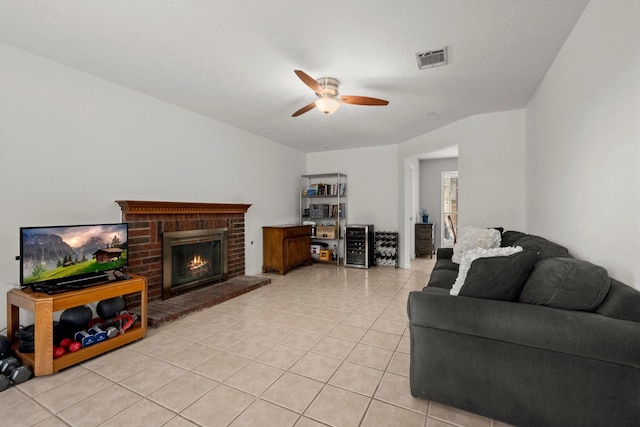 tiled living room featuring a brick fireplace and ceiling fan