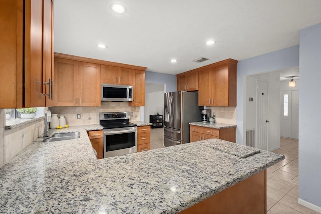 kitchen with sink, stainless steel appliances, tasteful backsplash, light stone countertops, and kitchen peninsula