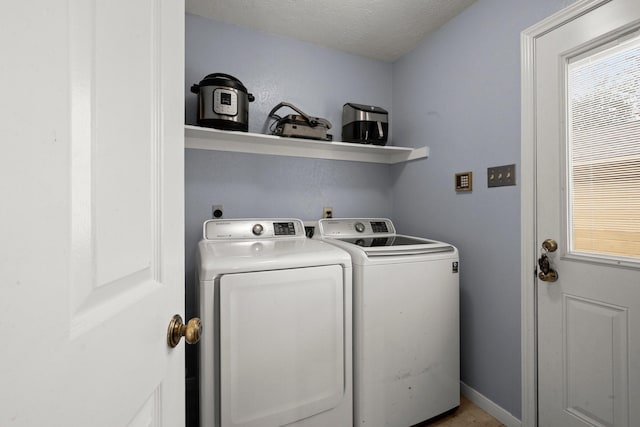 clothes washing area featuring a textured ceiling and washer and clothes dryer