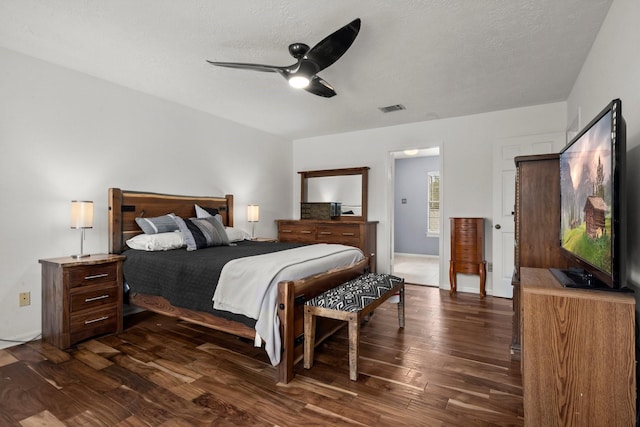 bedroom featuring dark wood-type flooring, a textured ceiling, and ceiling fan