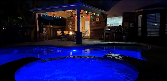 pool at twilight featuring an in ground hot tub, a patio area, and a fire pit