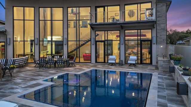 back house at dusk with a balcony and a patio area