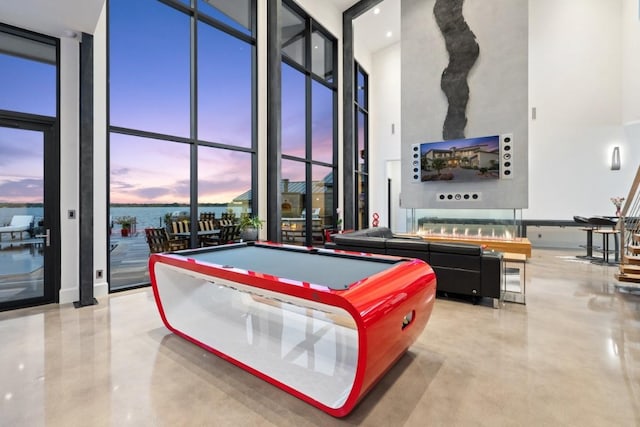 game room featuring a towering ceiling, floor to ceiling windows, and billiards