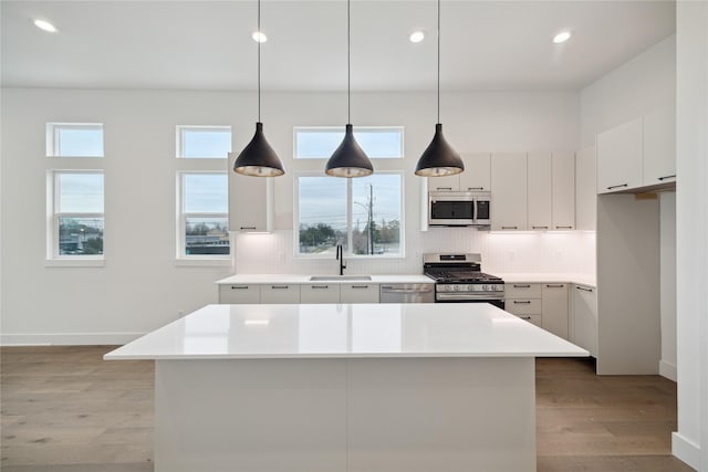 kitchen featuring pendant lighting, stainless steel appliances, a center island, and sink