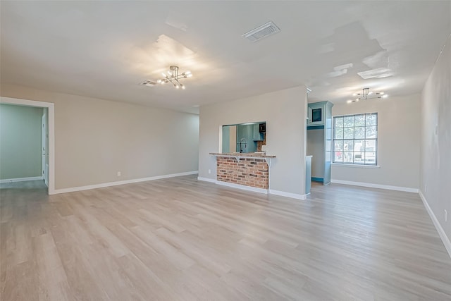 unfurnished living room with sink, light wood-type flooring, and a notable chandelier