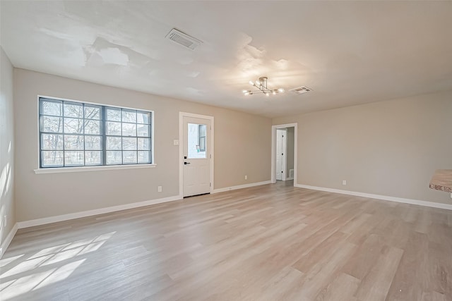 empty room with an inviting chandelier and light hardwood / wood-style flooring